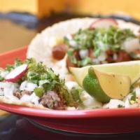 Beantown Tacos · Three soft corn tortillas with your choice of filling, topped with onions, cilantro, and a w...