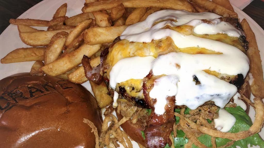 The Bacon Cheddar Ranch Burger (8 Oz) · charcoal grilled and topped with savory strips of bacon melted cheddar-jack cheese, served high on fresh cut fried-onion strings, and garnished with ranch dressing on a brioche bun. Served with fries.