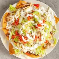 Nacho Supremo · A pile of nachos topped with refried beans, steak and pulled chicken, lettuce, tomato, sour ...