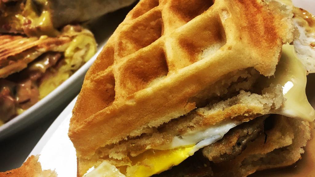 Maple Sausage Waffle Sandwich · This is a creation second to none!  Hearty breakfast sandwich that starts with a Belgian waffle & is  filled with maple sausage, 2 fried eggs, American cheese and maple syrup drizzle.  Topped with powdered sugar and served with an extra side of maple syrup.