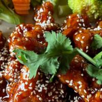 Sesame Chicken · Crispy fried chicken in a sweet and sour sauce, garnished with sesame seeds and steamed broc...