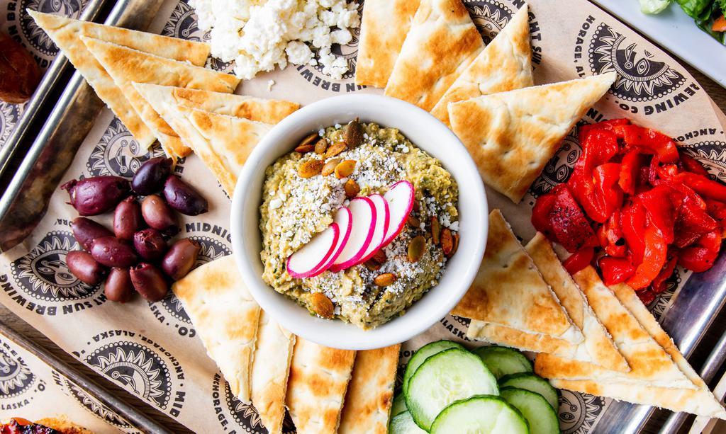 Green Chili Hummus · Vegetarian. Spicy and delicious hummus topped with spicy pepitas, cotija cheese & radish -  served with kalamata olives, roasted red peppers, feta, cucumber,  and warm pita points.