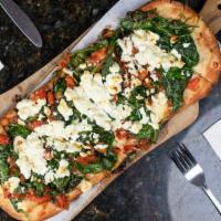 Spinach & Goat Cheese Flatbread · With tomato, garlic, and oil. Served on a wooden pizza board with a handle.