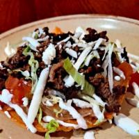 Birria Tostada · crispy corn tortilla spread with beans topped with lettuce tomatoes cheese and sour cream.