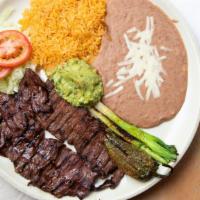 Carne Asada · Charbroiled skirt steak served with grilled green onions, guacamole, rice and beans.