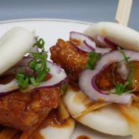 Hot Chicken Bao · Steamed bao buns stuffed with spicy soy-glaze chicken, Asian slaw, red onion, and scallion.