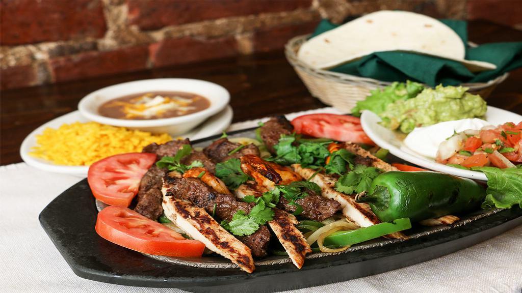 Grilled Chicken Fajitas · Grilled chicken fajitas are served over a bed of sauteed spanish onions, green peppers, celery and tomatoes. Accompanied with mexican rice, refried beans, guacamole, sour cream, pico de gallo and fresh flour tortillas. Garnished with cilantro and jalapeño.