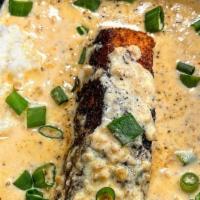 Blackened Salmon And Grits · Blackened salmon over a bed of cheese grits with creole sauce.