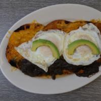 Huevos Rancheros · Two eggs, two crispy tortillas layered with black beans, salsa, cheddar cheese and avocado.
