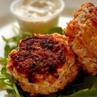 Salmon Cakes · Two salmon cakes with side of dill sauce
