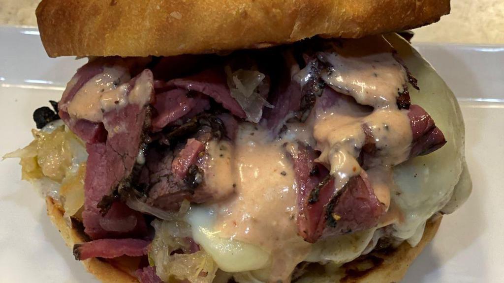 Reuben Burger · Start with grilled pastrami piled with a sweet relish/sauerkraut mix and topped with melted Swiss and provolone cheeses then our awesome sauce to complete the flavors! Served on our house-made bun. Served with a generous portion of our famous garlic fries.