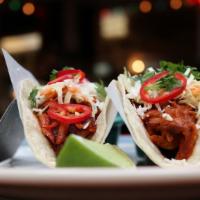 Brisket Tacos · Three flour tortillas filled with slow cooked brisket and topped with onions and cilantro.  ...
