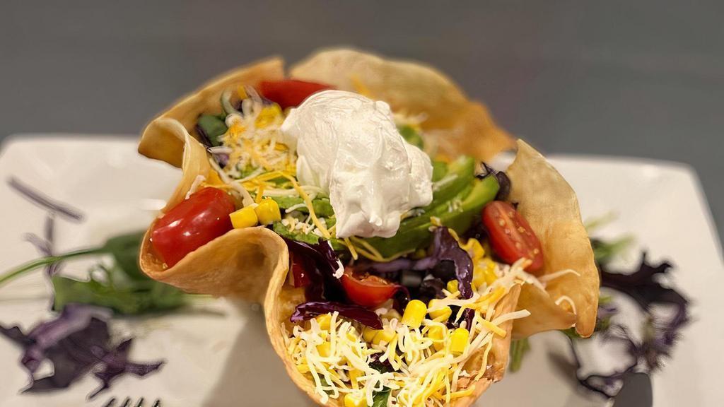 Taco Salad · large crispy flour tortilla shell filled with Romaine lettuce, mixed with tomatoes, red onions, beans and our house dressing. Topped with avocado, sour cream, shredded cheese and grilled chicken breast.