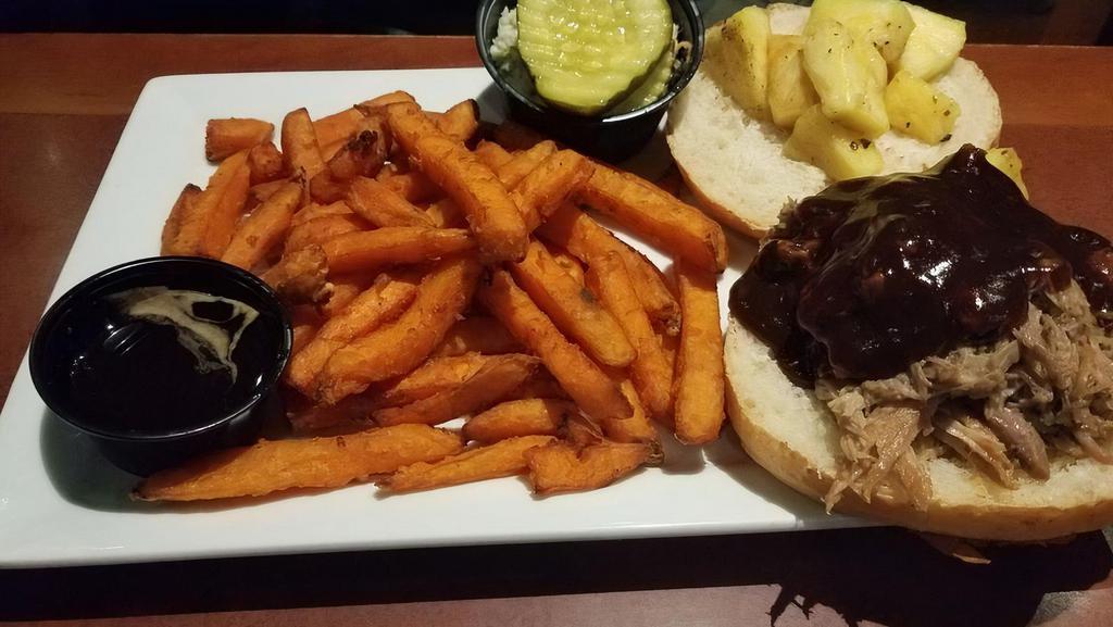 Bbq Pulled Pork Sandwich · Tender pulled pork in our homemade Southern comfort BBQ sauce with grilled pineapple on a country round roll with sweet potato fries. Served with French fries, pickles and coleslaw.