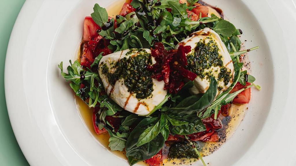 Burrata Capri · Burrata cheese with roma tomatoes and sun dried tomatoes served over arugula, garnished with basil, olive oil and balsamic drizzle.