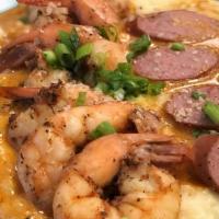 Shrimp And Grits · Six jumbo prawns over creamy cheddar grits topped with Cajun turkey sausage and roasted garl...