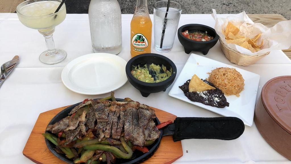 Skirt Steak Fajita · Served in a sizzling plate with corn tortillas, green & red peppers, & onions with rice & beans on the side.