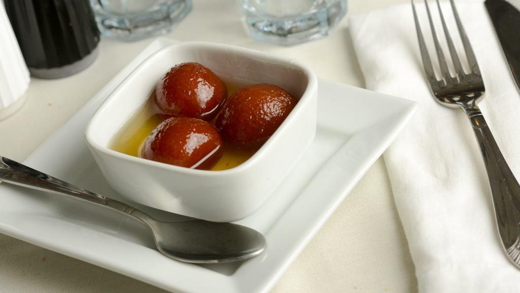 Gulab Jamun · Traditional deep-fried milk pastry served in rosewater and honey syrup with a sprinkle of coconut flakes.