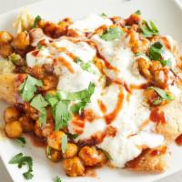 Samosa Chaat · Samosa topped with spiced chickpeas, sweet yogurt, tamarind and cilantro sauce garnished wit...