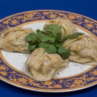 Manti · Large steamed meat dumplings, garnished with a drizzle of butter.