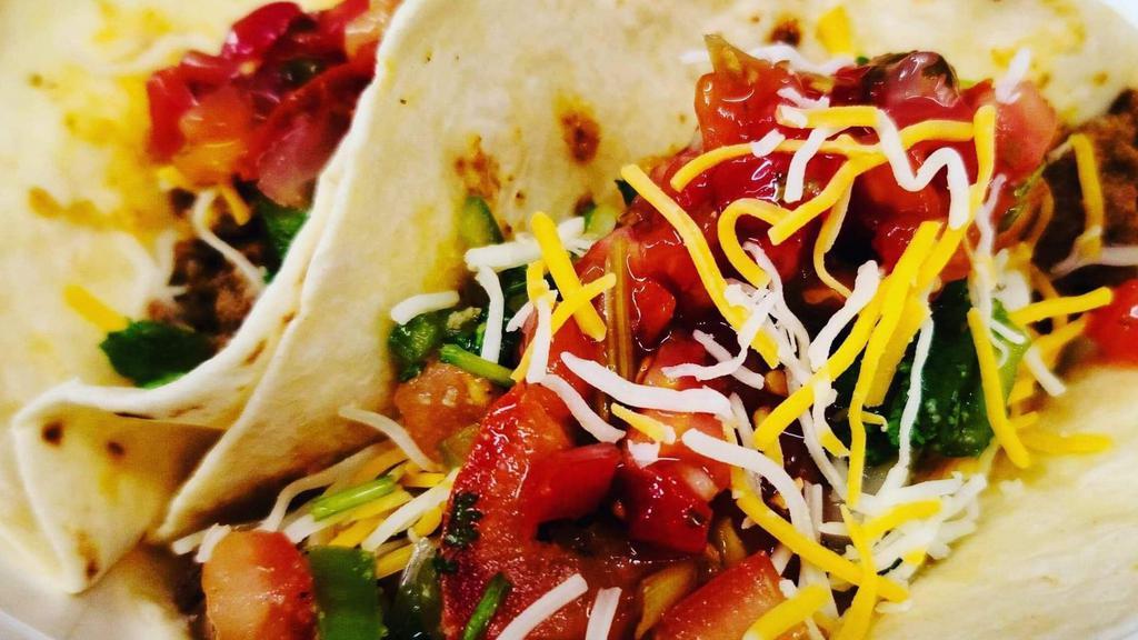 Tacos · Two perfectly seasoned ground beef, chicken, or steak, fresh lettuce, five blend cheese, topped with ripe tomatoes on flour tortilla.