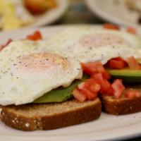 Avocado Toast · Two eggs over easy with sliced avocado, tomato, salt & pepper over multigrain toast