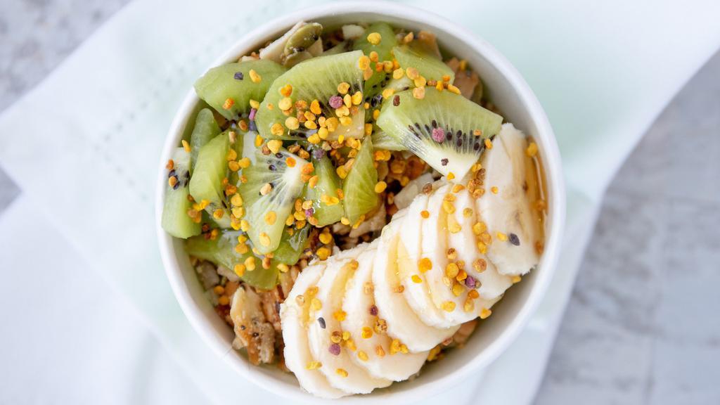 Pitaya Bowl · pink pitaya base topped with crushed coconut clusters (gf/contains pumpkin seeds), kiwis, bananas, and a drizzle of agave nectar