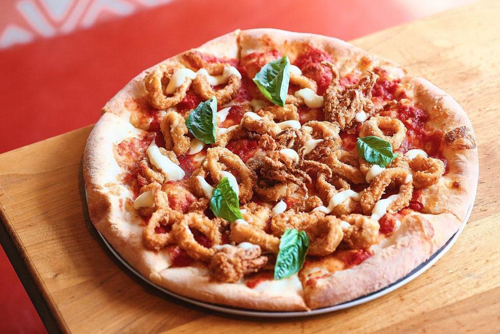 Crispy Calamari Pizza · Cheese-baked pizza dough topped with our American pizza sauce, a drizzle of garlic lemon aioli, and fried calamari.