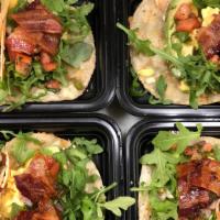 Breakfast Tacos · Two soft corn Tortillas filled with scrambled Eggs, Cheddar Cheese, Bacon, our house-made Pi...