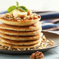 Banana Nut Buttermilk
Pancakes
 · Three perfectly fluffy banana nut pancakes served with a side of butter and syrup.