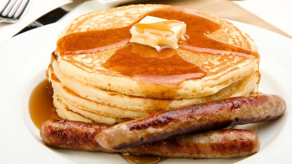 Sausage Buttermilk Pancakes · Three perfectly fluffy pancakes topped with pork sausage served with a side of butter and syrup.