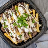 Beef Shawarma Fries · Beef shawarma over French fries topped with garlic sauce and tahini sauce.