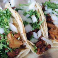 Tacos Al Pastor · Three corn or flour tortillas filled with marinated pork and pineapple. Topped with cilantro...