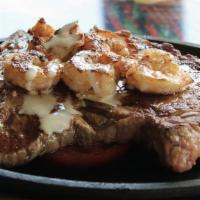 Steak Del Mar · T-bone steak, shrimp, and tomatoes grilled and seasoned, topped with cheese sauce. Served wi...