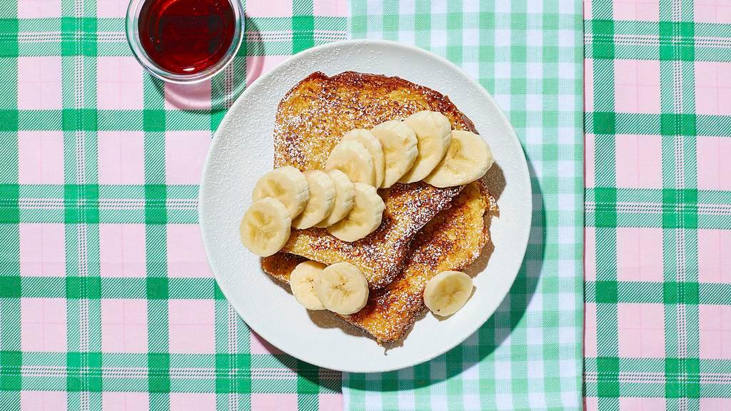 Le Banana French Toast · Just say “oui” to this delicious dish. Classic French toast topped with bananas and syrup on the side.