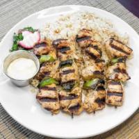 Chicken Shish Taouk · Two skewers of marinated chicken breast grilled over an open flame served with rice pilaf