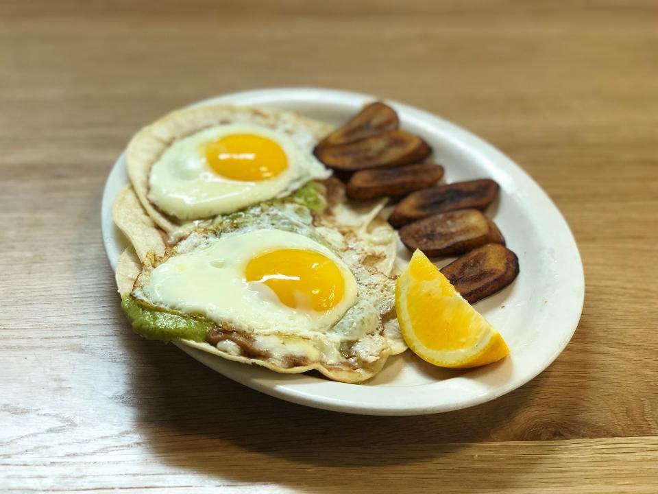 Huevos Rancheros* · Two eggs any style with tomatillo ranchero sauce, jack cheese,  . and refried beans on two corn tortillas. . Served with a side of fried plantains