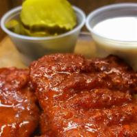 Nashville Hot Chicken · Nashville hot chicken fingers or wings served with a side of ranch and pickles.