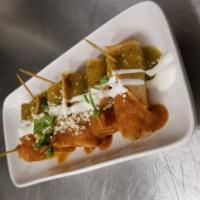 Banderillas Ahogadas · Crispy corn taqultos filled with chicken, topped with crema, green and red hot sauce, queso ...