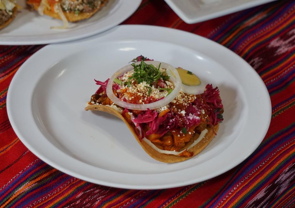 Enchiladas Guatemaltecas · Open face crispy corn tortilla topped with mixed vegetables and chicken, beets, cabbage, tomato sauce, boiled sliced eggs, onion and parmesan cheese.