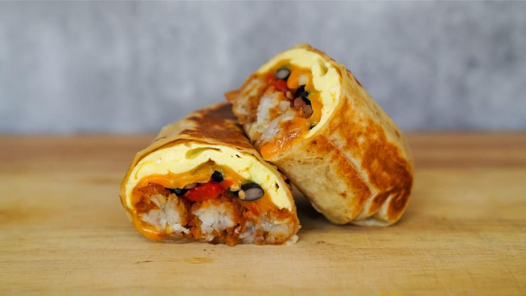 Huevos Rancheros Burrito · 3 fresh cracked cage-free scrambled eggs, melted Cheddar cheese, fire roasted red peppers, black beans, pico de gallo, and crispy potato tots wrapped in a toasted 12” flour tortilla with side of avocado salsa verde