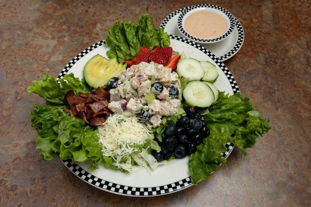 Fresh Berry Chicken Salad · This bright summer salad features our housemade chicken salad made fresh blueberries, celery, onion and mixed nuts.. Served on a bed of crisp hand-cut lettuce greens along with bacon, avocado, cucumber, Jack cheese, and fresh blueberries & fresh strawberries.  Served with your choice of dressing.
