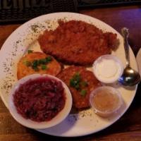 Wiener Schnitzel · A breaded pork cutlet served with two potato cakes and a side of red cabbage.