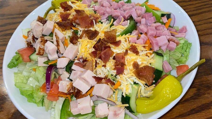 Cobb Salad · Mixed greens topped with apple smoked bacon, scallions, tomato, onions, egg and blue cheese crumbles with your choice dressing.
