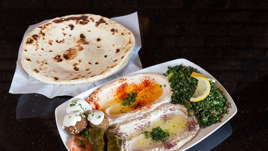 Mezze Plate Sampler · Vegetarian. Order of hummus, Baba ghanouj, tabouli salad, grape leaves and falafel topped with tahini sauce. Served with fresh baked flatbread.