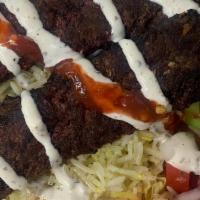 Beef Kebab Plate Over Salad · lettuce, tomato, cucumber, pickle, feta cheese, white sauce, and red sauce.