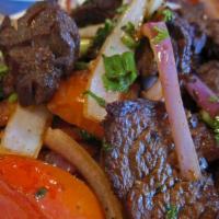 Lomo Saltado · Marinated tender steak sautéed with onions and tomatoes served over french fries and rice.