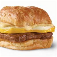 Sausage, Egg & Swiss Croissant · A fresh-cracked grade A egg and grilled sausage covered in creamy swiss cheese sauce on a fl...