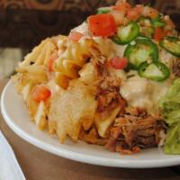 Hideaway Nachos · Gluten free. Pulled pork and creamy queso on a bed of crispy waffle fries, with refried bean...