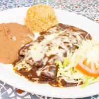 Enchiladas En Mole · Three chicken enchiladas topped with mole sauce and white cheese, with a side of lettuce and...